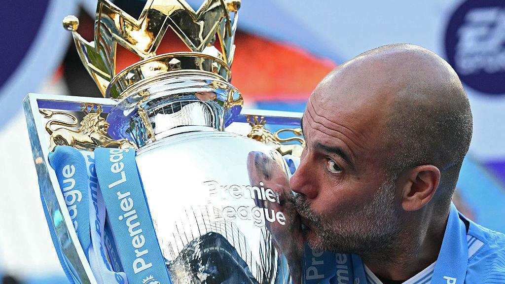 Pep Guardiola kissing the Premier League trophy