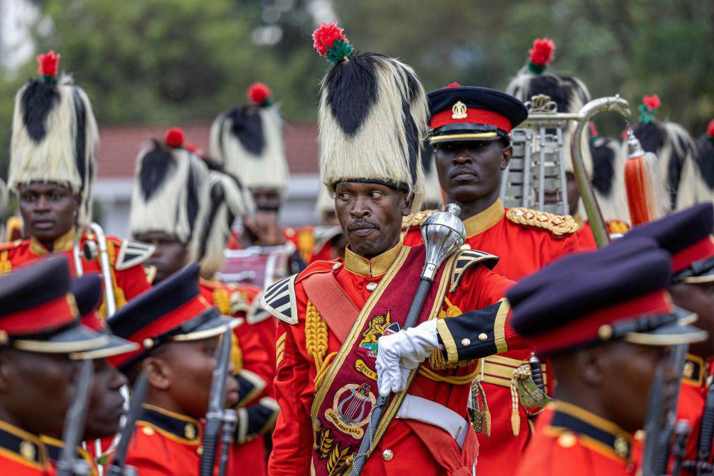 Kenyan soldiers in red ceremonial dress march on a parade. 