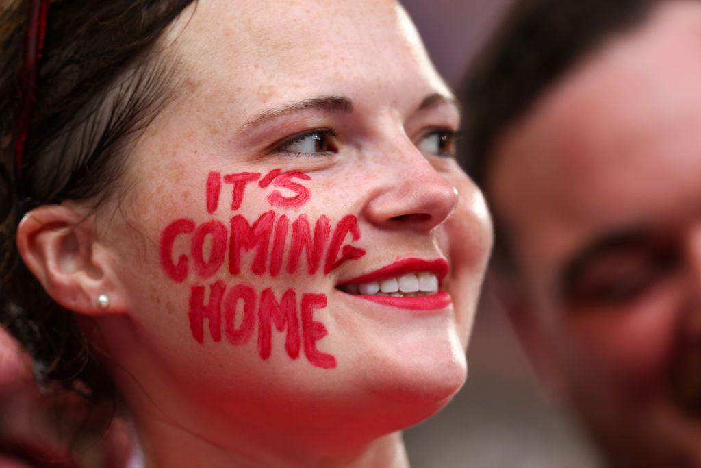 Fan with 'it's coming home' painted in red on her face. 