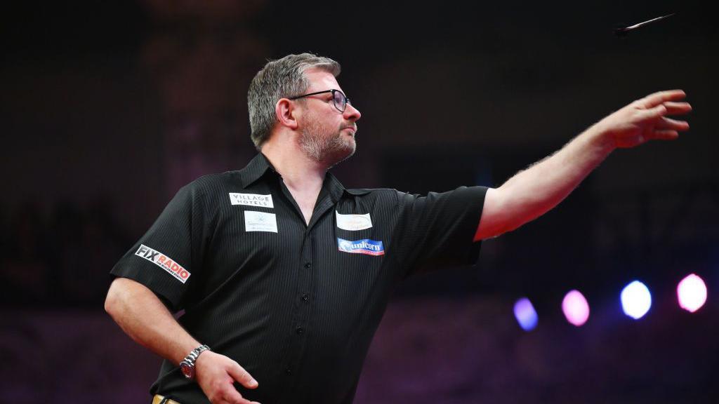 James Wade of England throws against Luke Humphries of England during the 2024 Betfred World Matchplay semi-finals at Winter Gardens on July 20, 2024 in Blackpool, England. 