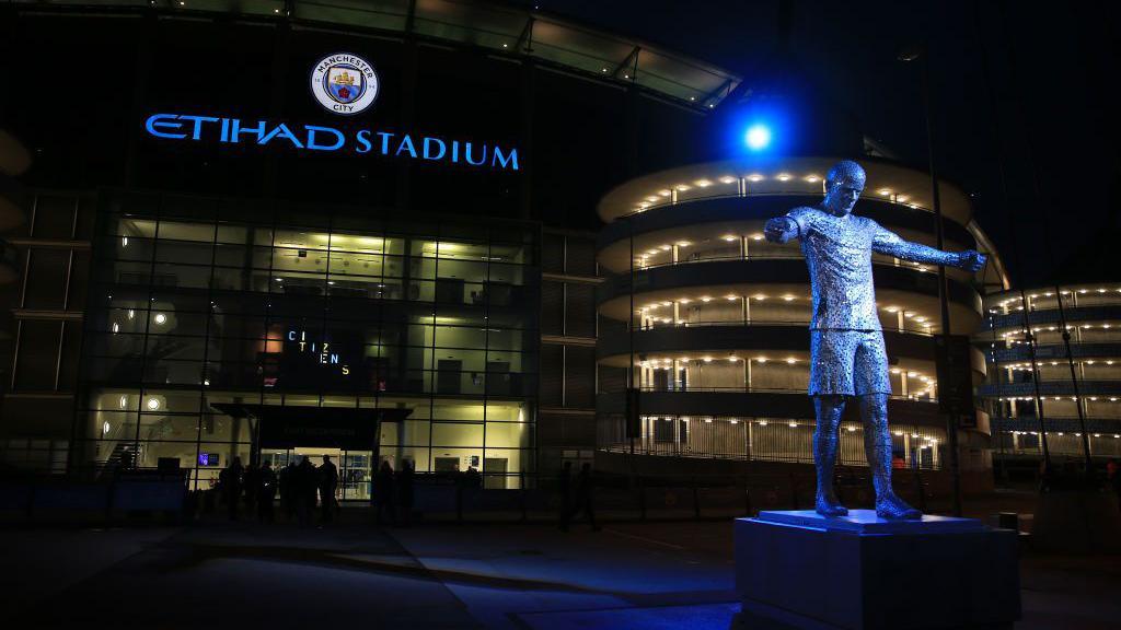 A statue of former Manchester City player Vincent Kompany is illuminated with a blue light before the Premier League match between Manchester City and Brentford at Etihad Stadium on February 9, 2022 in Manchester, United Kingdom