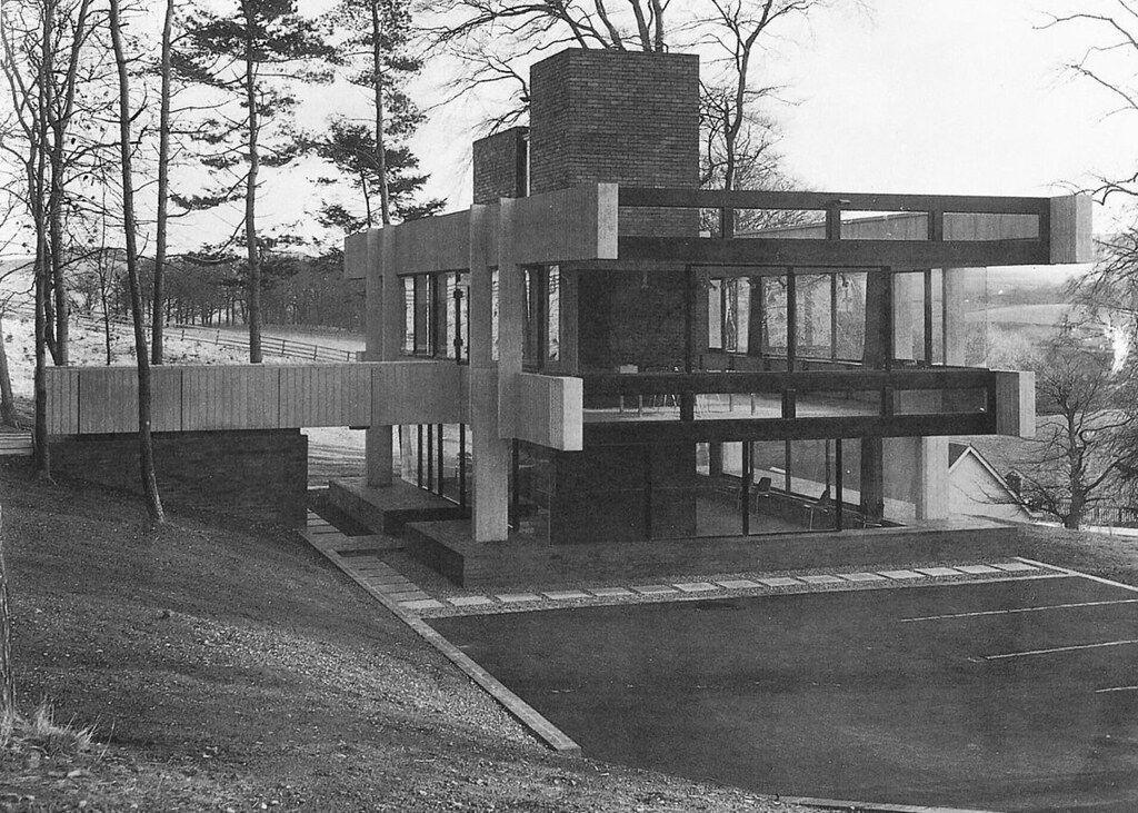 A black and white image of the a brutalist studio many years ago when it was in its prime with clean concrete, wood and brick lines and wide open spaces around it