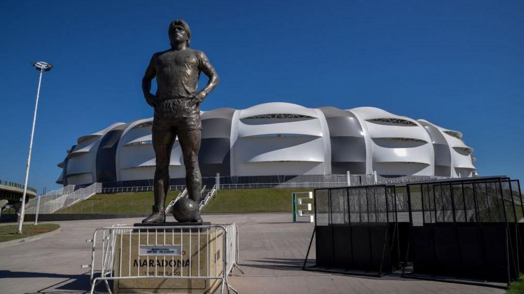A statue of Diego Maradona stands outside Estadio Unico Madre de Ciudades
