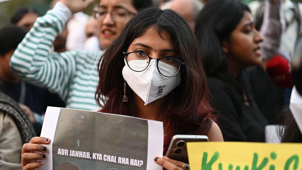 A woman wearing a mask holds a poster during a protest on 9 November demanding the government take action to reduce air pollution in Delhi