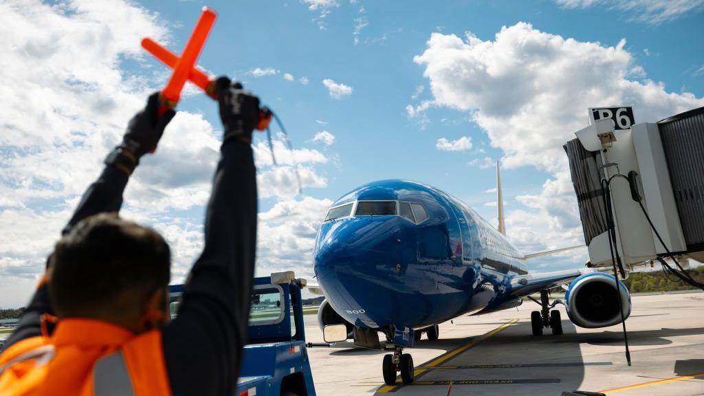 A ramp agent directs a Southwest Airlines Boeing 737-800 airplane in to a gate at Baltimore-Washington Airport (BWI) in Baltimore, Maryland, US, on Friday, April 12, 2024.