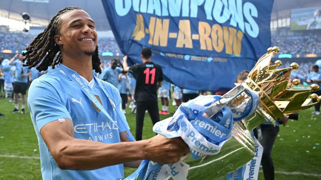 Nathan Ake holds the Premier League trophy