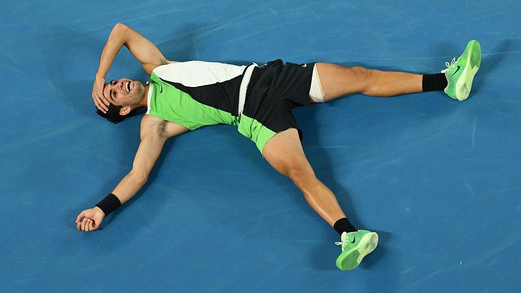 carlos celebrates his win by laughing and lying down