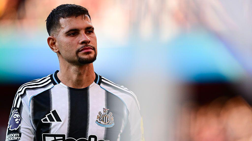 Bruno Guimaraes wearing Newcastle's black and white striped kit