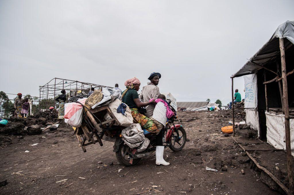 A man, woman and child prepare to drive off on a motorbike loaded with possessions