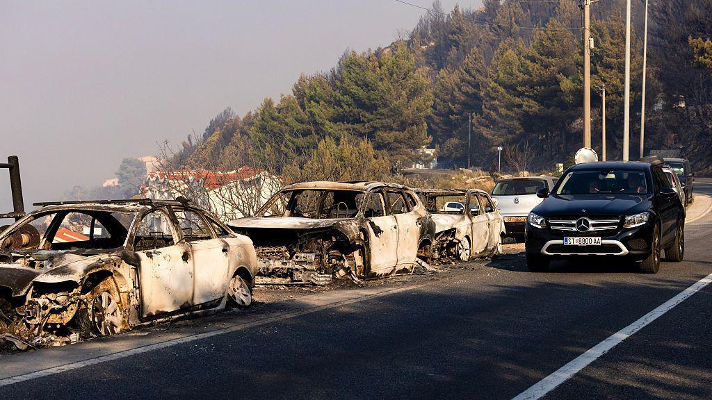 A firefighter truck is parked next to burnt cars on a road after a wildfire near the town Omis, some 30 kilometres south of Split.