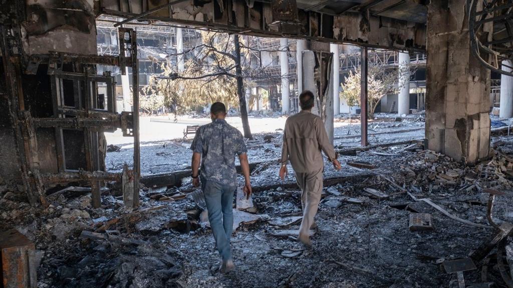  Two unidentified security men walk through the debris of the headquarters of the Islamic Republic of Iran News Network, which was destroyed in Israeli strkes
