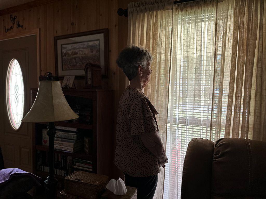 Karen Bowden stands for a portrait in her living room, staring out the window.