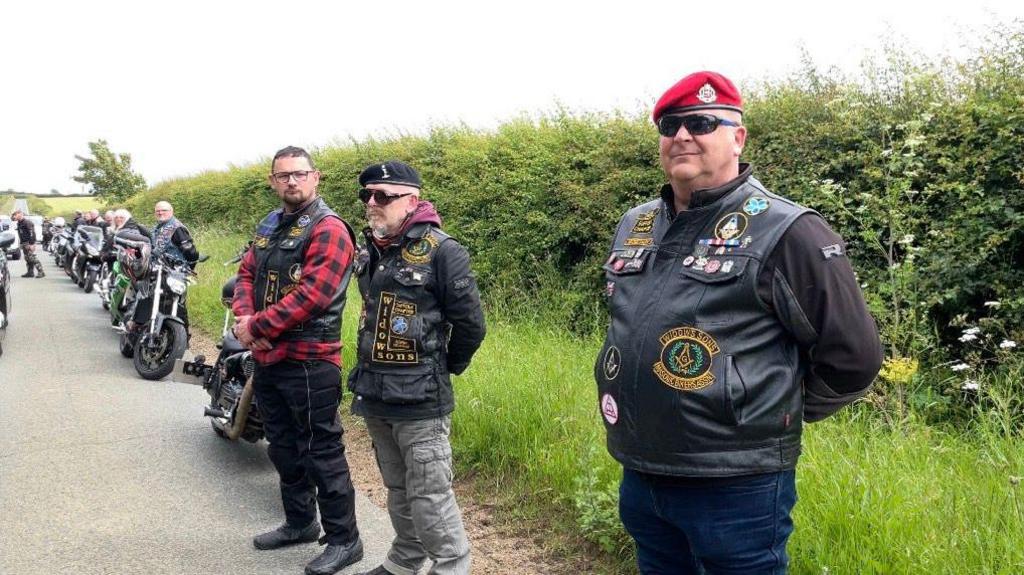 Motorcyclists create a guard of honour by the side of the road at Bill Gladden's funeral