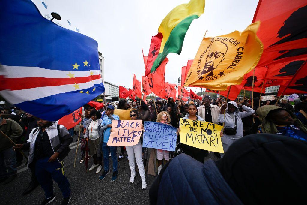 Demonstrators carry placards and flags while they march from Marques de Pombal square to Praça dos Restauradores to protest he death of Cape Verdean immigrant.