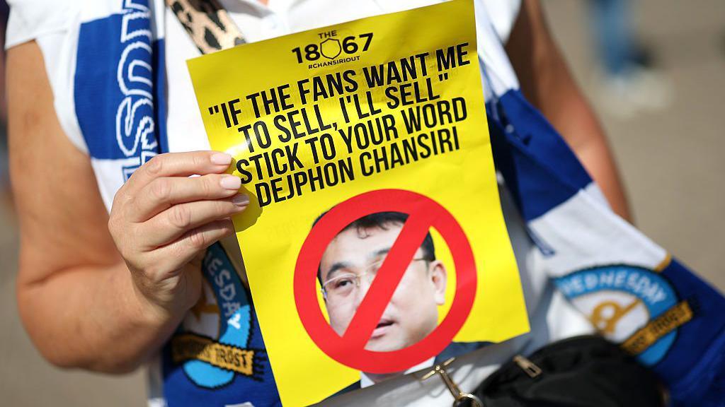 A Sheffield Wednesday supporter holds up an anti-Dejphon Chansiri leaflet before a match