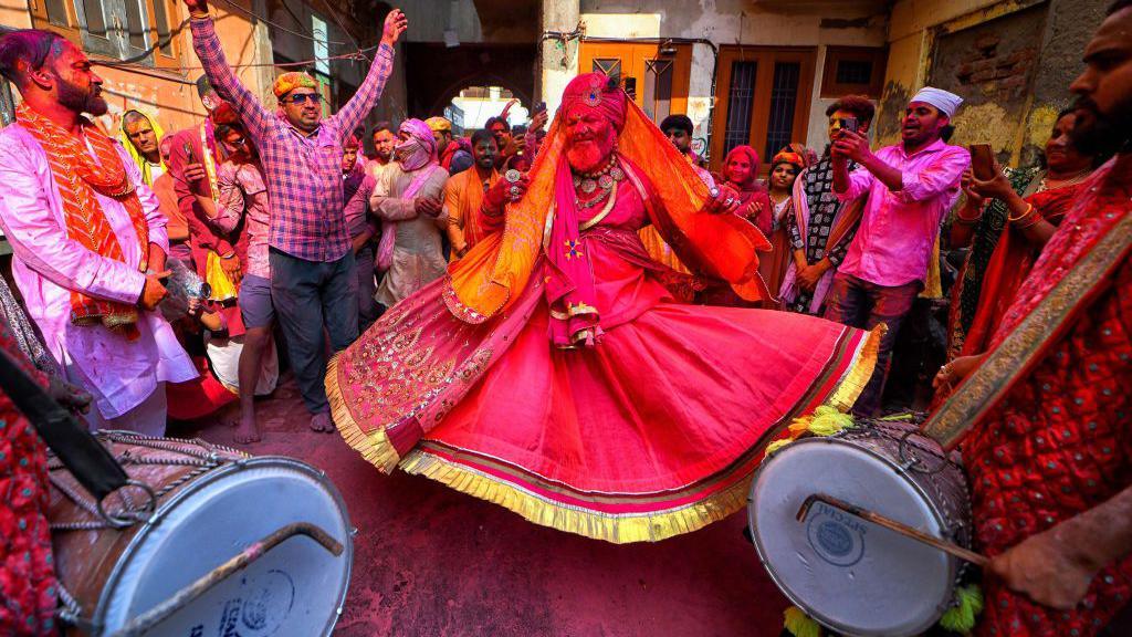 A priest wearing traditional Indian cloth seen dancing to the beats of drum