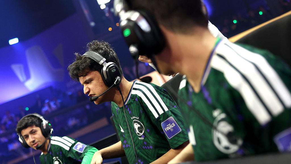 Three Esports players wearing green Saudi Arabia t-shirts in ana arena, wearing black headphones with microphones on them