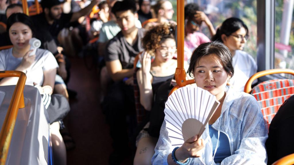 A person uses a fan to cool down on a TfL bus service as the UK experiences its hottest June day on record during a heatwave in East London, Britain, 24 June 2026.