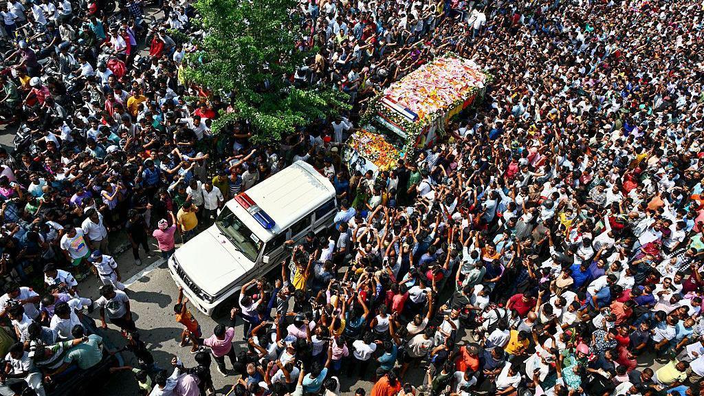 A police van followed by a garlanded vehicle carrying Zubeen Garg's body surrounded by thousands of fans and admirers in Guwahati city on 21 September