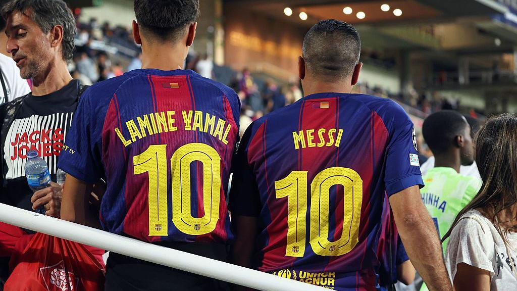 Two Barcelona fans wear football shirts with number ten on the back, the left bearing the name of Lamine Yamal and the right the name of Lionel Messi