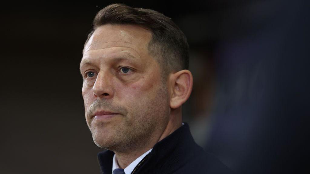 Leam Richardson looks on while stood in the Rotherham dugout