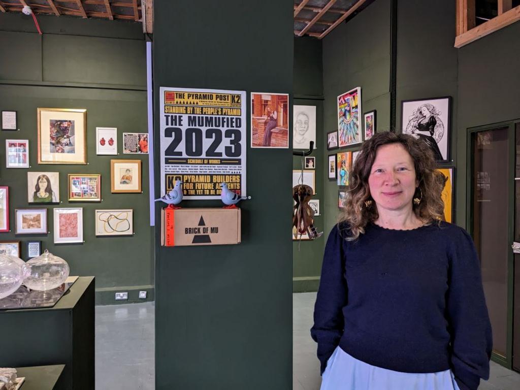 A smiling woman in front of a wall of art