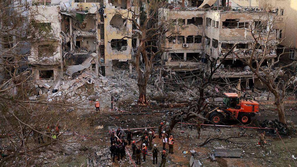 Rescuers stand amid the debris of damaged building in the Israeli city of Tel Aviv following an Iranian missile attack on June 16, 2025