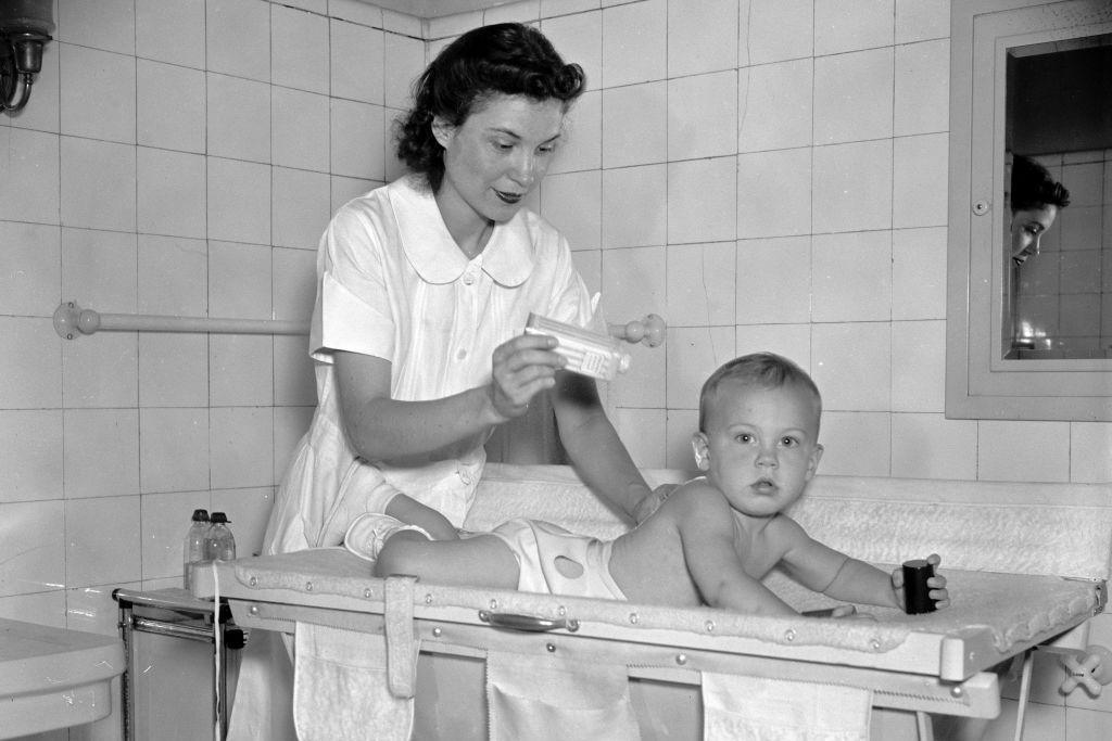 Baby being given a bath - a woman putting baby powder on baby - circa 1937-1939.