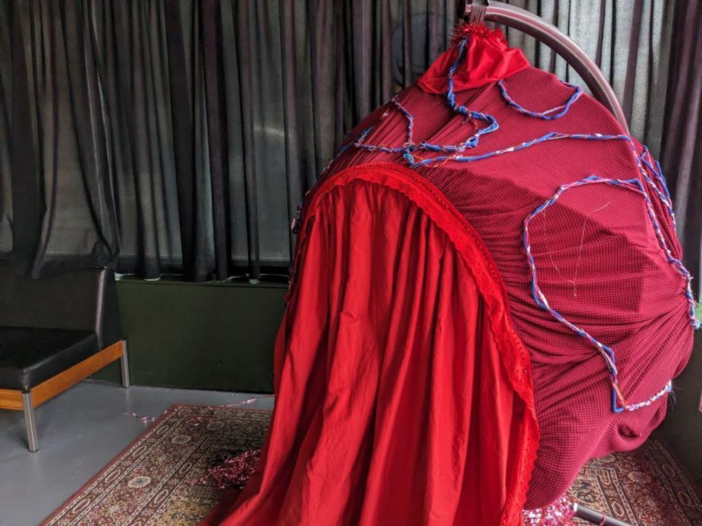 hanging chair draped in red textiles