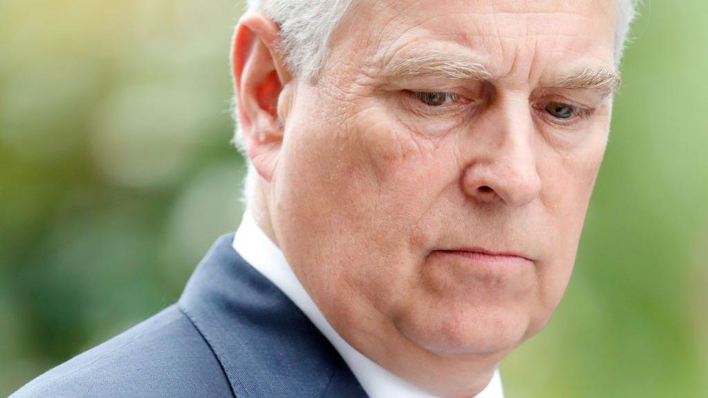 Prince Andrew in a suit looking towards the ground