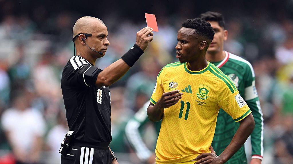 Brazilian referee Wilton Sampaio shows a red card to South Africa's midfielder Themba Zwane.