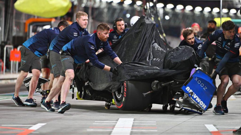 The Williams mechanics wheel the damaged remains of Franco Colapinto's Williams back into the garage