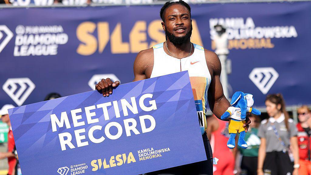 Kishane Thompson celebrates with his meeting record placard
