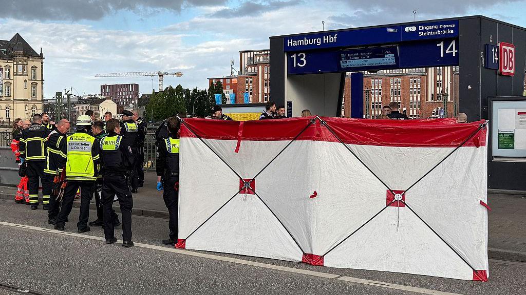 A white barrier in front of platforms 13 and 14 with emergency services staff nearby