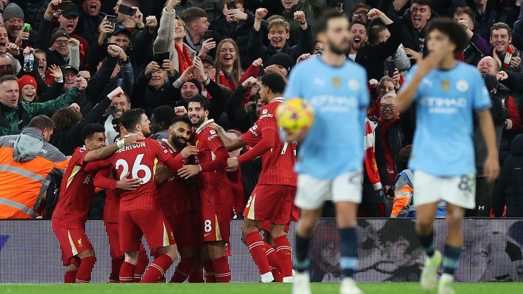 Manchester City players look dejected as they walk away from Liverpool players who are celebrating their 2-0 win at Anfield. 