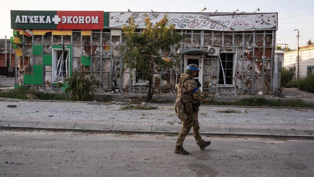 A Ukrainian soldier walks on an empty street in front of a badly damaged building in Sudzha, Russia, in August.