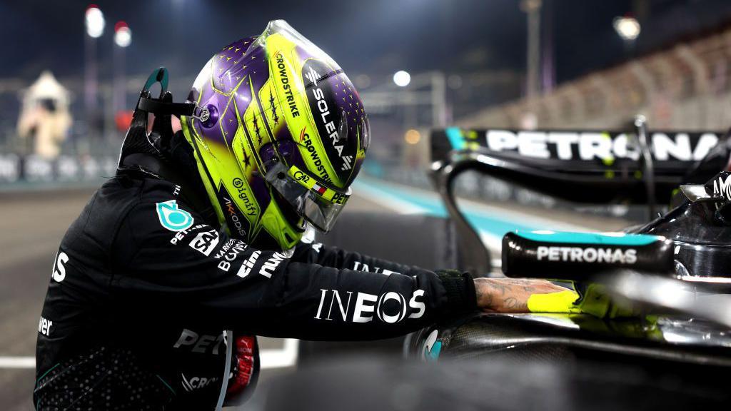 Mercedes' Lewis Hamilton leans against his car after finishing the Abu Dhabi Grand Prix