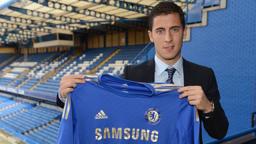 Eden Hazard holds up a Chelsea shirt