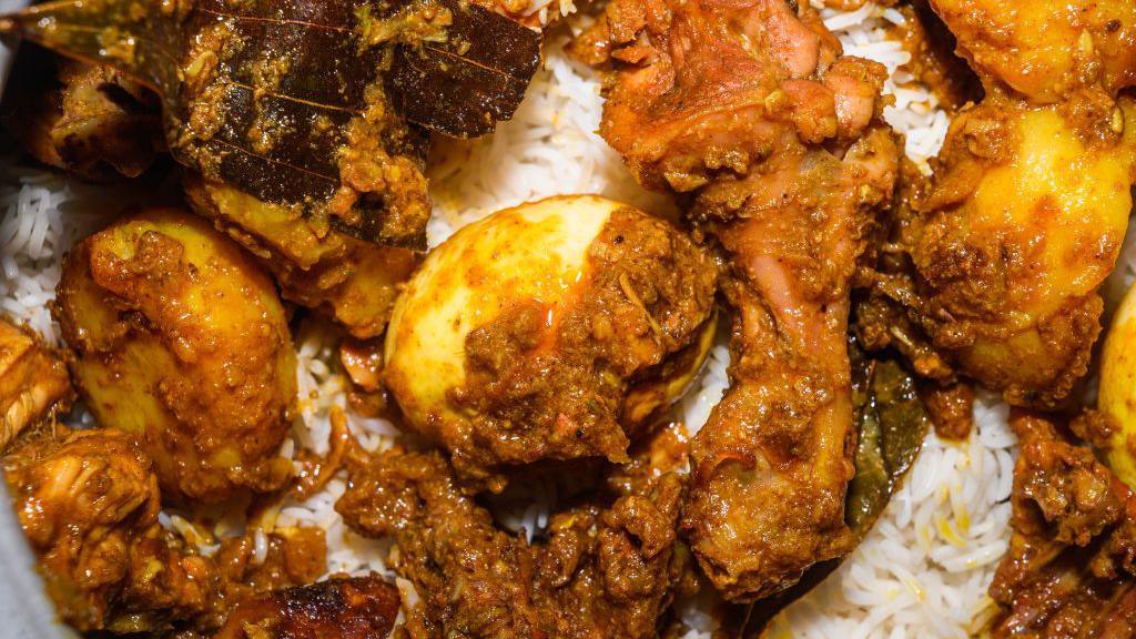 A pot of biryani, with aromatic basmati rice, cooked chicken, eggs and dry spices