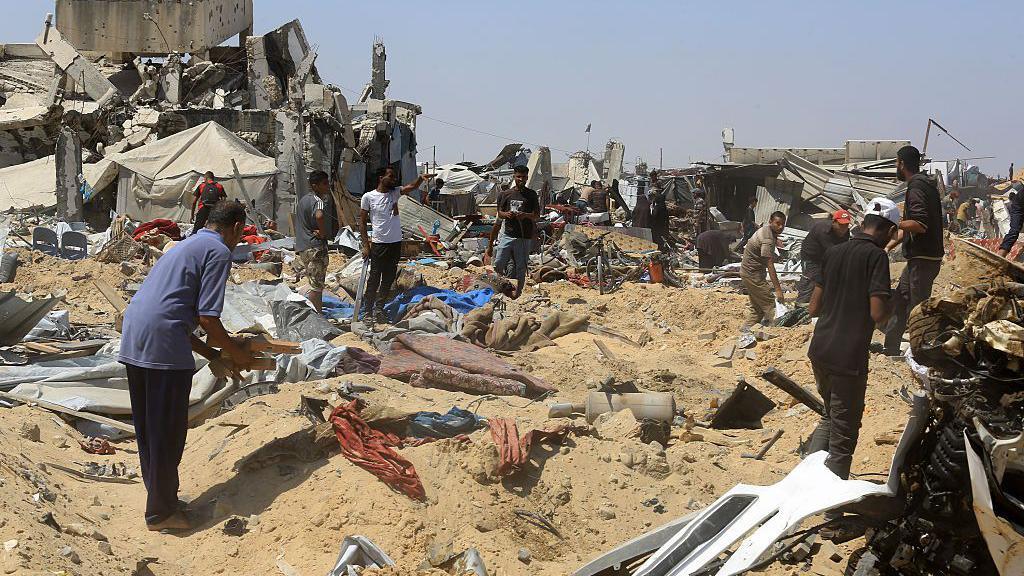 People search for belongings after Israeli tanks and bulldozers operated in an area where there was a tent camp, in Khan Younis, southern Gaza (11 July 2025)