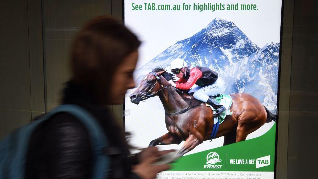 A woman walks past a betting advertisement