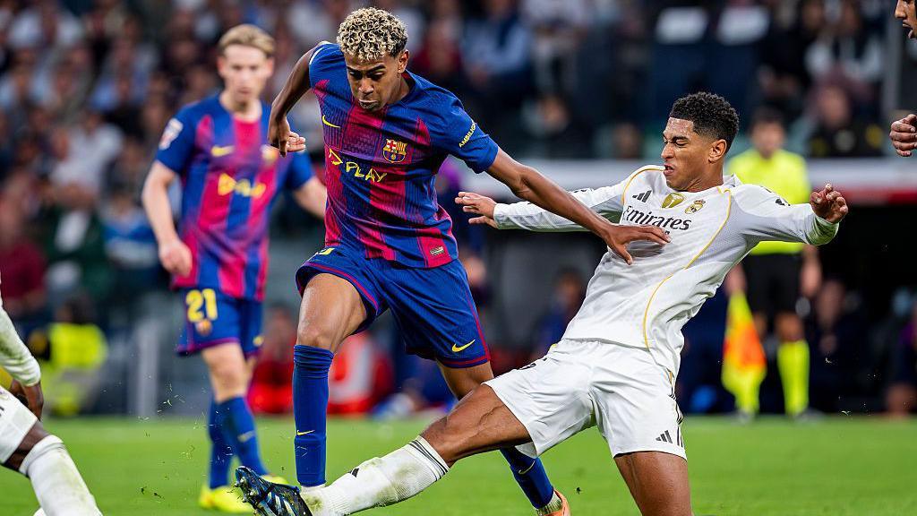 Barcelona's Lamine Yamal is tackled by Jude Bellingham of Real Madrid