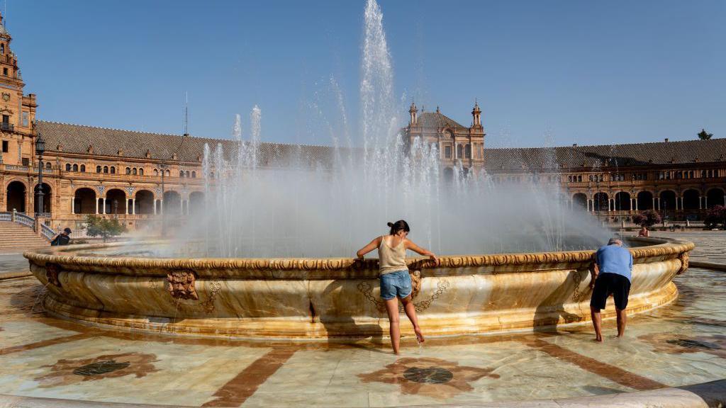People cool off in the fountain in the Plaza de España in Seville.