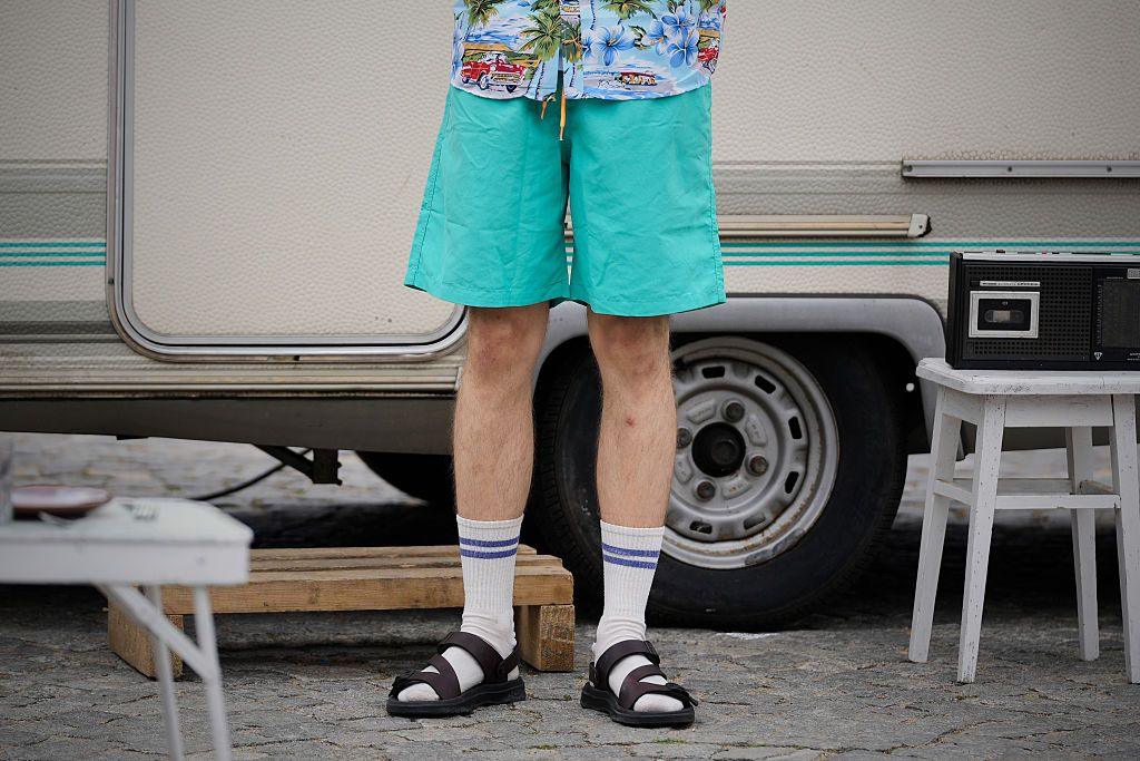 Man wearing green shorts, socks and sandals