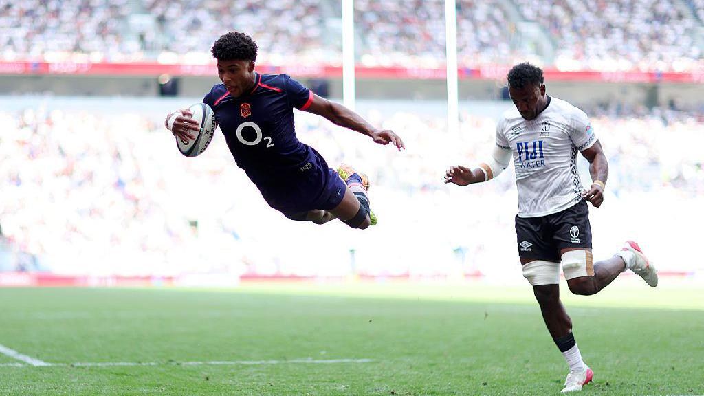 Noah Caluori dives over the line to score a try for England