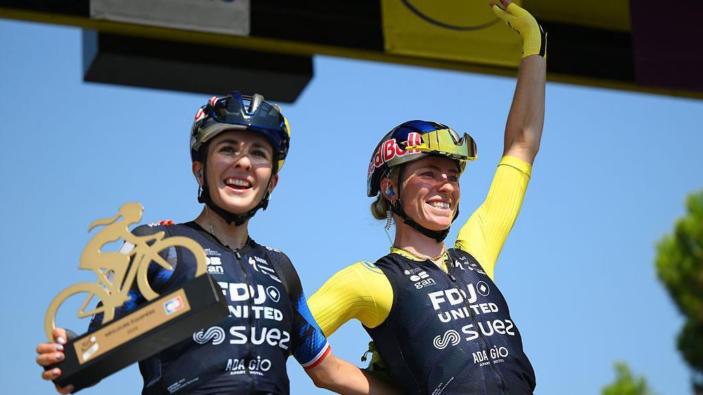 Juliette Berthet with the best domestique trophy beside team-mate Demi Vollering prior to the final stage of the 2026 Tour de France Femmes