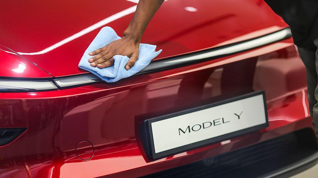 A worker cleans a Tesla Model Y electric vehicle at the newly opened Tesla Inc. store at Bandra Kurla Complex (BKC) in Mumbai, India, on Tuesday, July 15, 2025. 