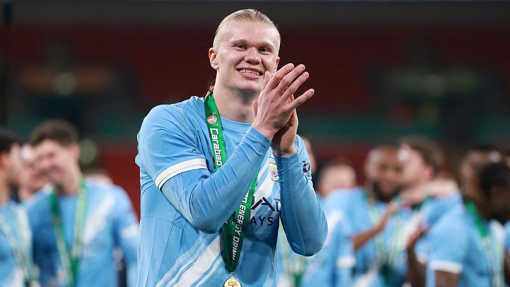 haaland smilling and clapping in his man city outfit.