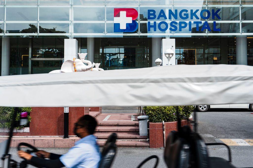 A man drives a vehicle in front of the Bangkok Hospital