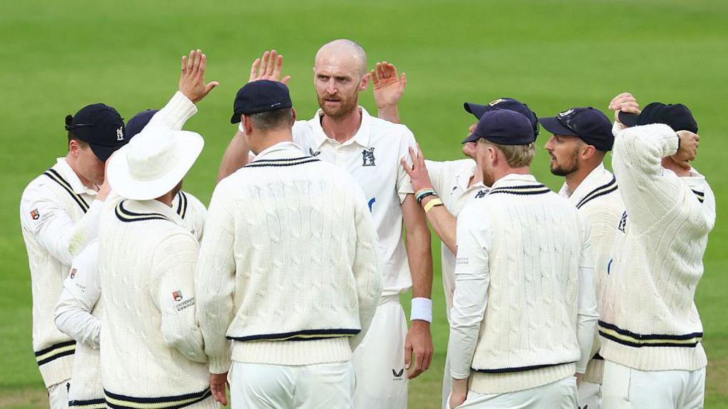 Olly Hannon-Dalby celebrates with his Warwickshire team-mates after taking a wicket against Yorkshire